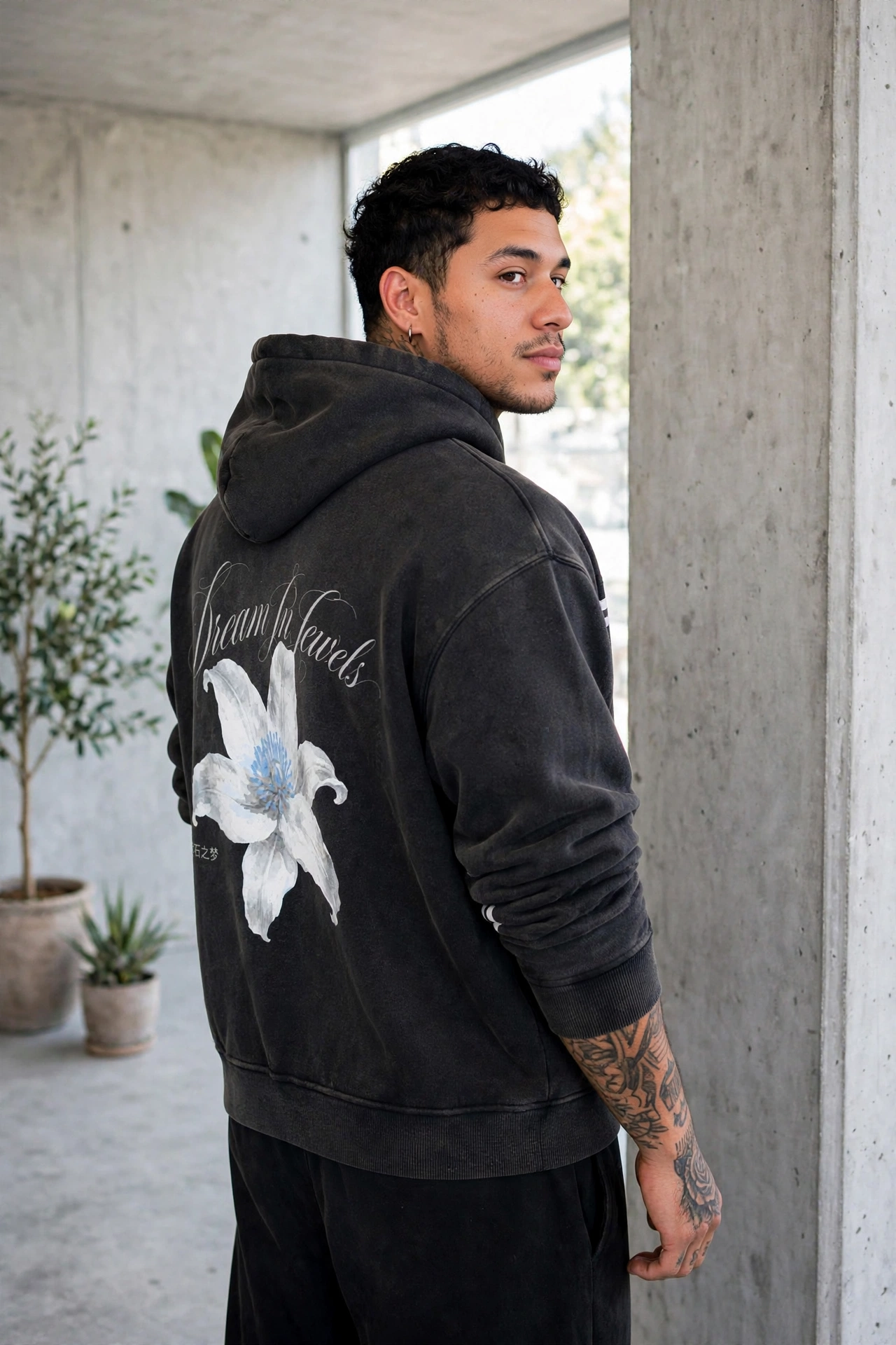 Model in the Dyme Maizon washed black lily hoodie against a concrete wall